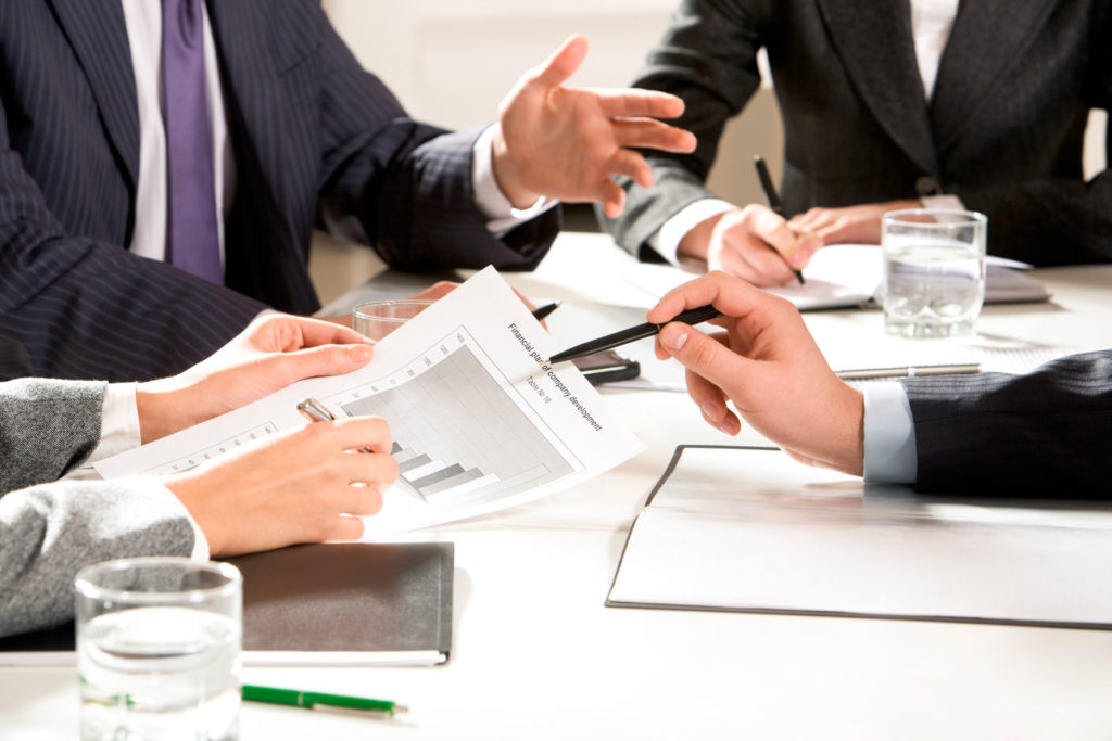 Consultants and clients sitting around a table, reviewing financials and business model drivers